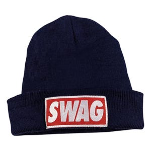 Könnte beinhalten: Eine marineblaue Mütze mit einem roten Patch, auf dem "SWAG" in weißen Buchstaben steht.