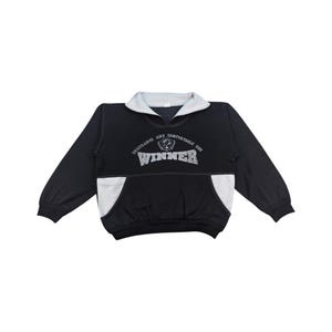 Könnte beinhalten: Schwarzes Sweatshirt mit grauem Kragen und Taschenakzenten. Das Wort "WINNER" ist in einer Used-Schriftart auf die Brust gedruckt, darüber die Worte "ENDURANCE AND COMFORTABLE USE". Das Sweatshirt hat lange Ärmel.