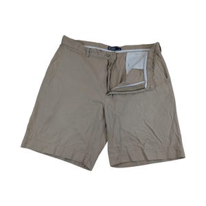 Könnte beinhalten: Eine Khaki-Shorts mit Reißverschluss und Knopfverschluss. Die Shorts haben ein Markenetikett am hinteren Bund.