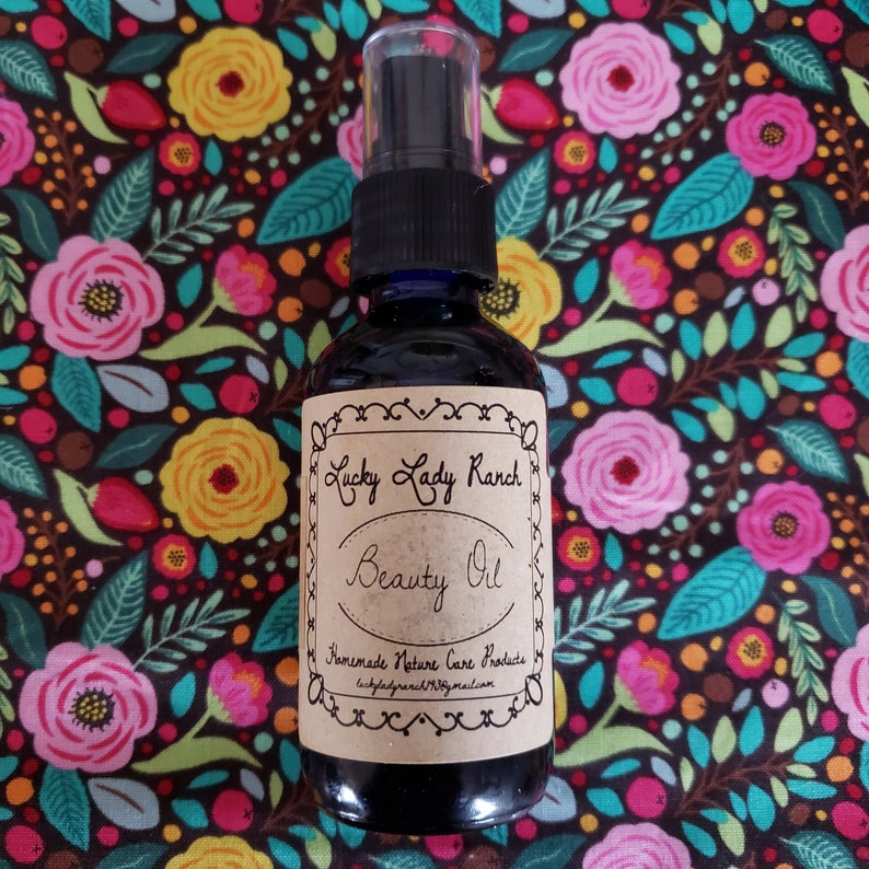 May include: A brown glass bottle with a black spray top and a brown paper label that reads "Lucky Lady Ranch Beauty Oil Homemade Nature Care Products luckyladyranch@gmail.com".