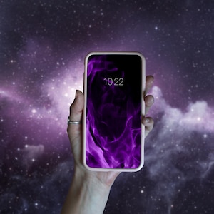 Puede incluir: Un teléfono inteligente rosa con un diseño abstracto de llamas púrpuras y negras en la pantalla. La hora 10:22 se muestra en la pantalla.