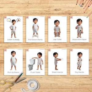May include: Eight flashcards on a wooden surface, each depicting a step in a bathroom routine. The cards show a cartoon boy performing actions like listening to his body, pulling down pants, using the toilet, and wiping with paper. Other cards show pulling up pants, flushing, washing, and drying hands.