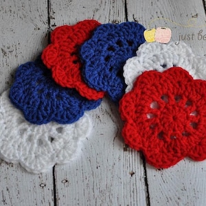 May include: Six crocheted flower shapes in red, white, and blue. The flowers are arranged in a semi-circle.
