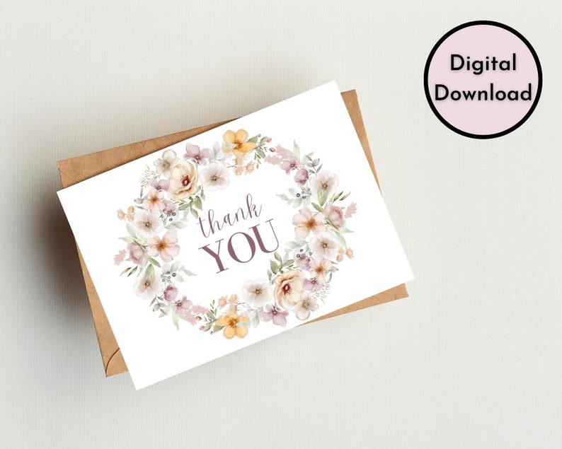 May include: A white card with a floral wreath design in shades of pink, yellow, and green. The text "thank you" is written in purple inside the wreath.
