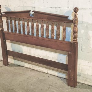 May include: A vintage wooden headboard with a warm brown finish. The headboard features decorative spindles and finials, with a classic design. The headboard is approximately 60 inches wide and 48 inches tall.