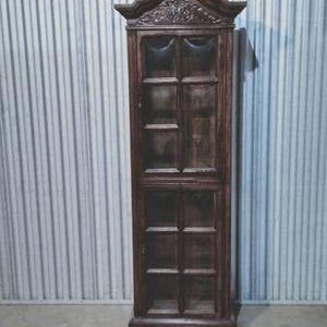 May include: A tall, dark brown wooden cabinet with glass-paned doors. The cabinet has a decorative top with carved details and a rectangular shape. The cabinet is approximately 72 inches tall.