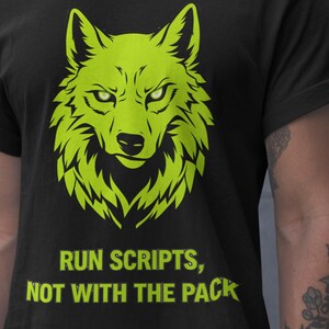 Puede incluir: Camiseta negra con un diseño de cabeza de lobo verde neón. El texto "RUN SCRIPTS, NOT WITH THE PACK" está impreso debajo del lobo. La camiseta está hecha de un material suave.