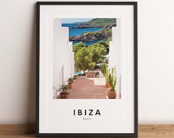 May include: A framed print featuring a photograph of a white building with a staircase leading up to a view of a blue ocean and green trees. The text "IBIZA Spain" is printed below the image.