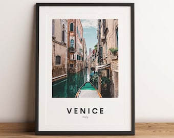 May include: A framed photograph of a narrow canal in Venice, Italy. The canal is lined with buildings and a small boat is in the water. The text "VENICE" and "Italy" is printed below the image.