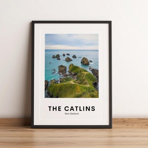 May include: A black framed print with a photo of a rocky coastline in New Zealand. The text "THE CATLINS" and "New Zealand" is printed below the photo.