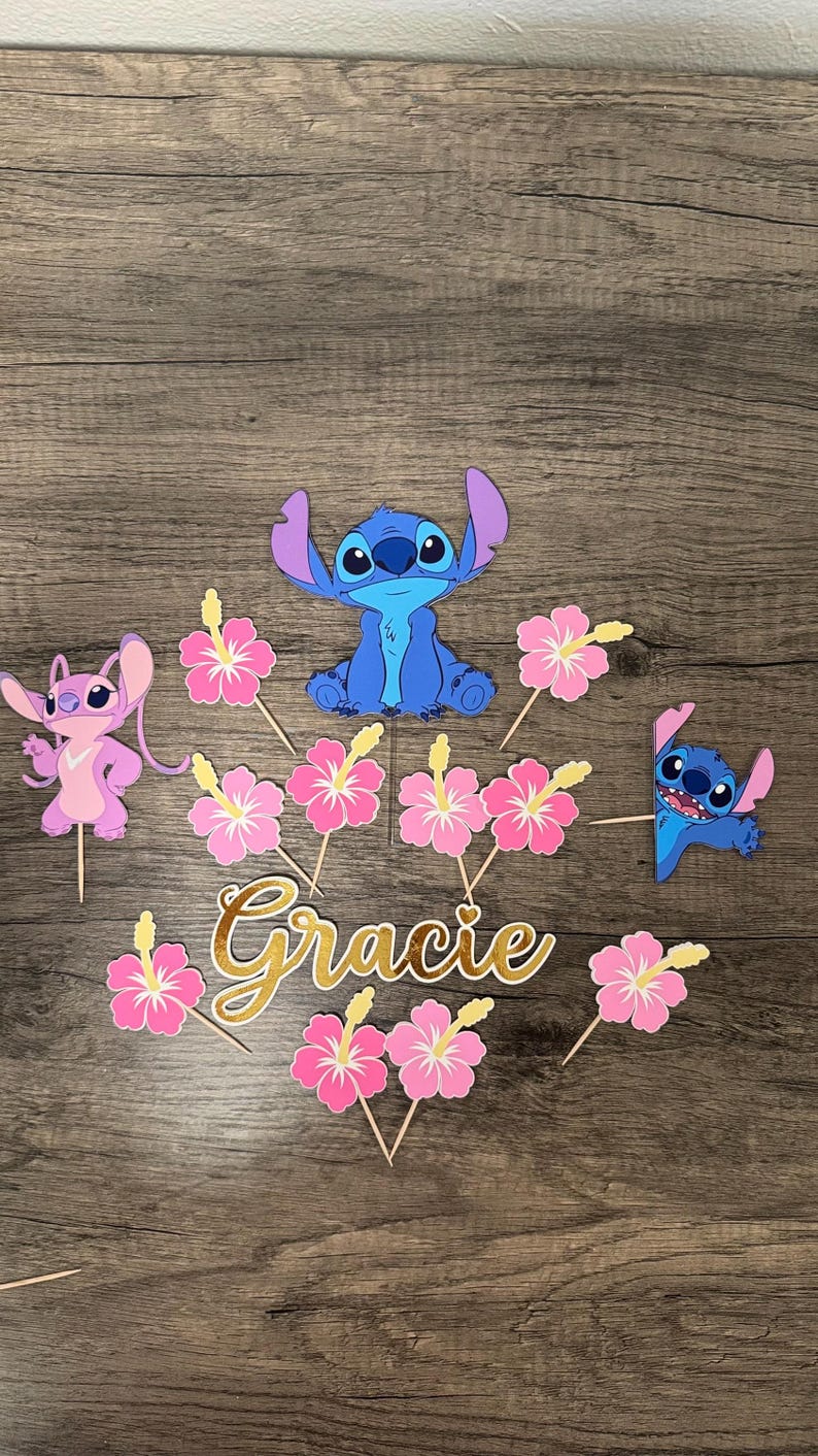 May include: Cake toppers featuring the character Stitch in blue, Angel in pink, and pink hibiscus flowers. The name "Gracie" is written in gold script. Perfect for a themed birthday party.