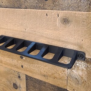 May include: Black plastic wall-mounted organizer with six slots. The organizer is mounted on a wood wall.