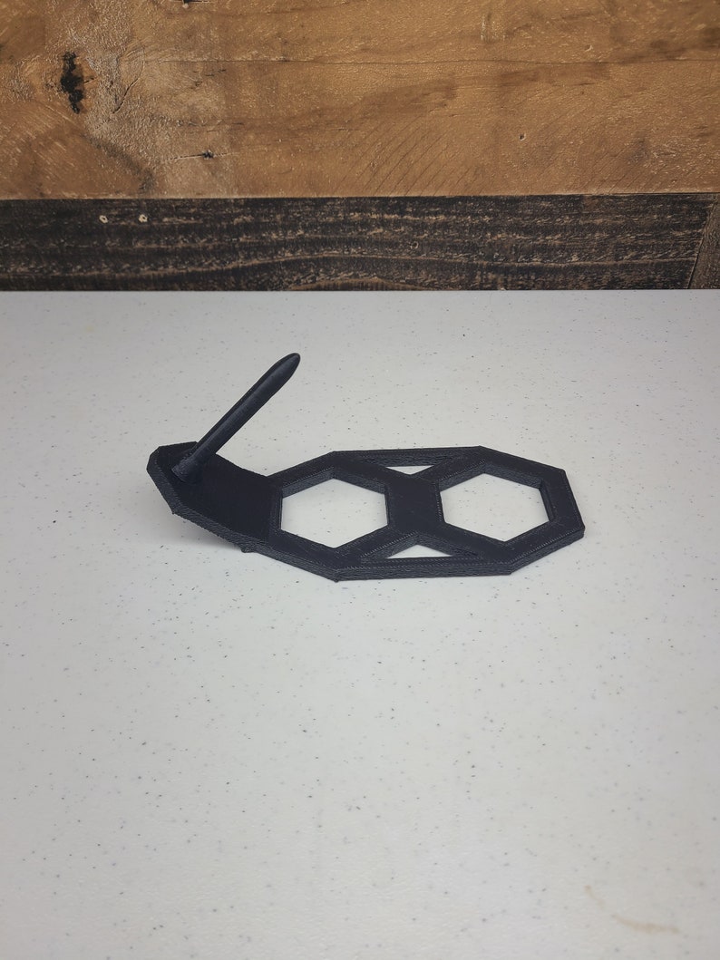 K&ouml;nnte beinhalten: Ein schwarzer, 3D-gedruckter sechseckiger St&auml;nder mit einem Stifthalter. Der St&auml;nder ist aus Kunststoff und hat ein geometrisches Design.