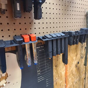 May include: A black plastic magazine holder with multiple magazines inserted. The holder is mounted on a pegboard wall. The holder has a label that reads "ECONOMY "B-27".