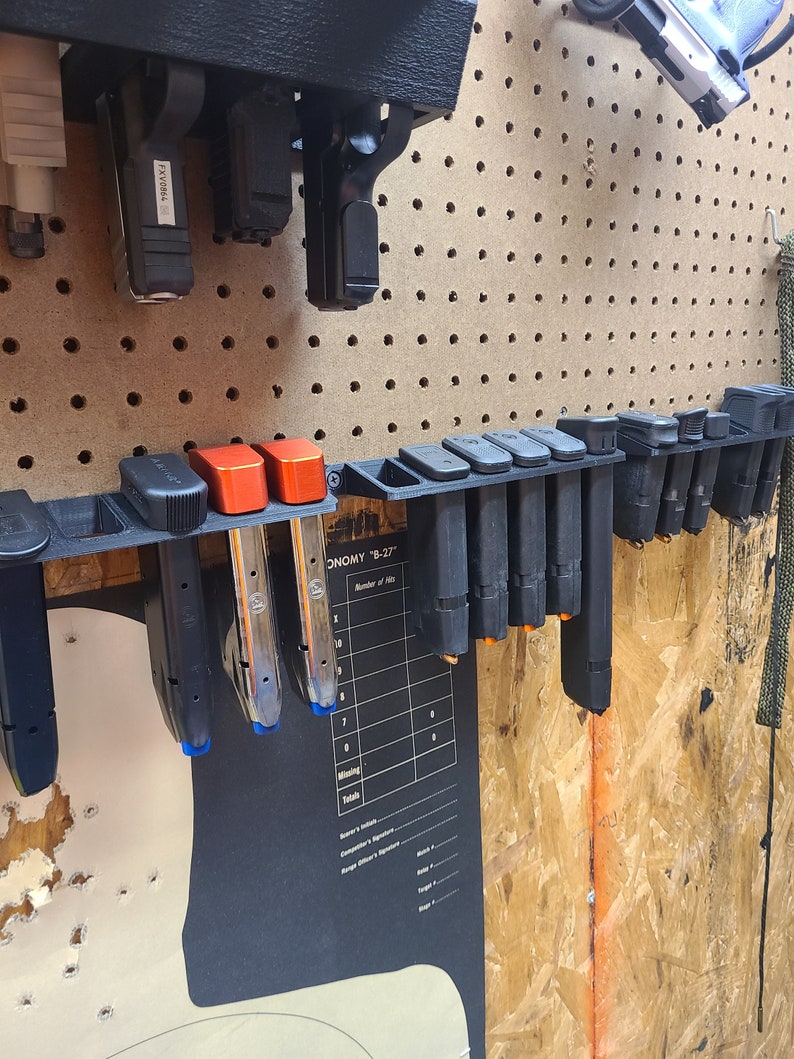 May include: A black plastic magazine holder with multiple magazines inserted. The holder is mounted on a pegboard wall. The holder has a label that reads "ECONOMY "B-27".