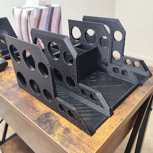 May include: A black plastic desk organizer with multiple compartments and holes for pens, pencils, and other office supplies. The organizer is sitting on a wooden table.