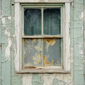 May include: A weathered wooden window with peeling green paint. The window has two panes on top and two panes on the bottom. The window is set in a white frame.
