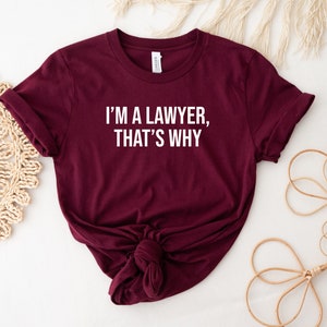 May include: Burgundy t-shirt with white text that reads "I'm a lawyer, that's why".