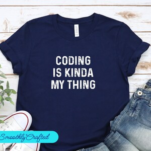 May include: A navy blue t-shirt with white text that reads "Coding is kinda my thing".