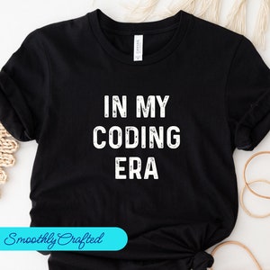 Puede incluir: Camiseta negra con texto blanco que dice "In My Coding Era".