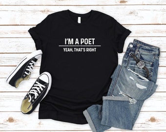 Puede incluir: Camiseta negra con texto blanco que dice "Soy un poeta, sí, así es". La camiseta está colocada sobre una superficie de madera blanca con un par de zapatillas negras y blancas y unos vaqueros azules.