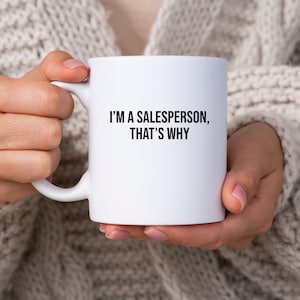 May include: White ceramic mug with black text that reads "I'm a salesperson, that's why".
