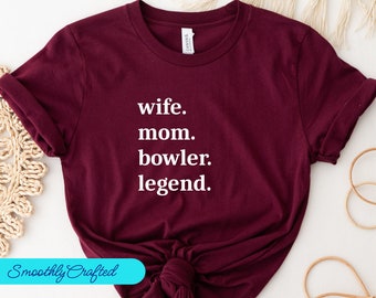 May include: Burgundy t-shirt with white text that reads "wife. mom. bowler. legend."