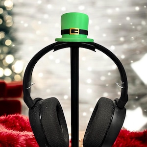 Könnte beinhalten: Schwarze Kopfhörer mit einem grünen Leprechaun-Hut auf dem Ständer.