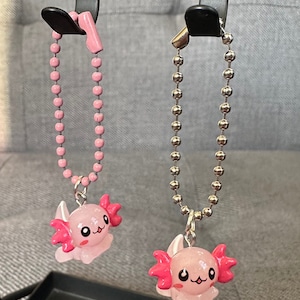 May include: Two pink axolotl charms on chains. One charm has a pink chain and the other has a silver chain.