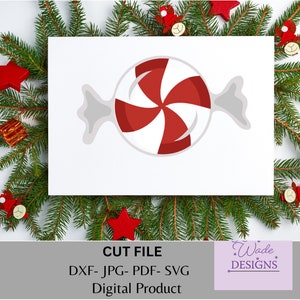 May include: A red and white peppermint candy with a white wrapper. The candy is in the shape of a traditional candy cane. The image is on a white background with a green pine branch border.