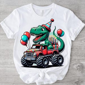 Może przedstawiać: Biała koszulka z zielonym dinozaurem w czapce urodzinowej, jadącym czerwonym monster truckiem. Dinozaur trzyma prezent, a na ciężar&oacute;wce są świeczki. W tle są też balony.