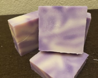 May include: Three bars of handmade soap with a swirl pattern of purple and white.