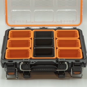 Puede incluir: Una caja de herramientas de pl&aacute;stico negra con un interior naranja. La caja de herramientas tiene varios compartimentos para organizar art&iacute;culos peque&ntilde;os. La tapa est&aacute; abierta, revelando los compartimentos vac&iacute;os.