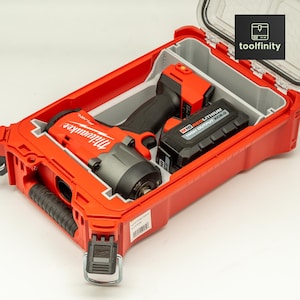 Könnte beinhalten: Ein roter Milwaukee Schlagschrauber und ein Akku in einem roten, harten Kunststoffkoffer mit einem durchsichtigen Deckel. Der Koffer hat einen Verschluss und einen Griff.