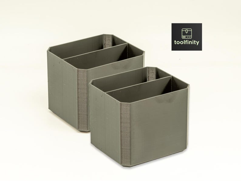 May include: Two gray plastic desk organizers with two compartments each. The organizers are made of a textured plastic and have a modern design.
