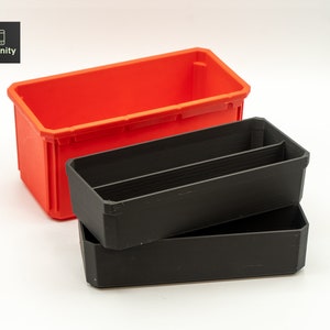 以下が含まれることがあります： 赤と黒のプラスチック製の収納ボックス2個。黒いボックスは赤いボックスの上に積み重ねられています。