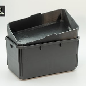 Puede incluir: Contenedores de almacenamiento negros de dos piezas. El contenedor superior está en ángulo con un interior texturizado. El contenedor inferior es rectangular con asas. El logotipo de Toolfinity está en la esquina superior izquierda.