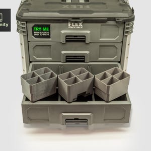 Puede incluir: Un sistema de almacenamiento de herramientas FLEX Stack Pack gris con tres cajones y contenedores de almacenamiento grises extraíbles. El cajón superior tiene una pegatina que dice "TRY ME PUSH & CLICK SHUT TO LOCK". El logotipo de toolfinity está en la esquina superior izquierda.