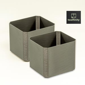 May include: Two gray square-shaped storage containers with a textured surface. The containers are made of a sturdy material and have a simple design.