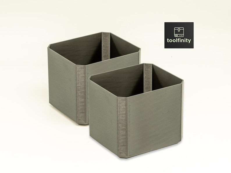 May include: Two gray square-shaped storage containers with a textured surface. The containers are made of a sturdy material and have a simple design.