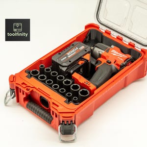 May include: An open red toolbox containing a black and red impact wrench, a battery, and a set of sockets. The toolbox has a clear lid and the text "toolfinity" is in the upper left corner.