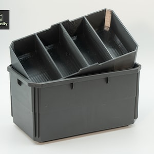 Puede incluir: Una caja de almacenamiento de plástico negro con un inserto divisor de plástico negro. El divisor tiene tres compartimentos.