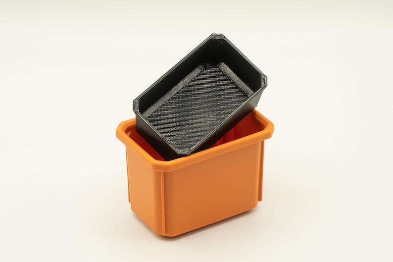 May include: A black plastic storage bin with a smaller black plastic bin inside. The larger bin is orange.