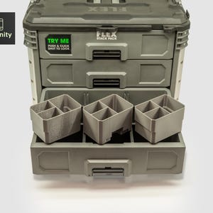 Puede incluir: Un sistema de almacenamiento de herramientas FLEX Stack Pack gris con tres cajones y contenedores de almacenamiento grises extraíbles. El cajón superior tiene una pegatina verde que dice "TRY ME PUSH & CLICK SHUT TO LOCK". El logotipo de toolfinity está en la esquina superior izquierda.
