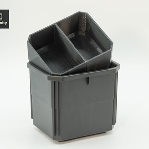 Peut inclure: Deux contenants de rangement en plastique noir, l'un empilé sur l'autre. Le conteneur supérieur a un séparateur au milieu, créant deux compartiments.