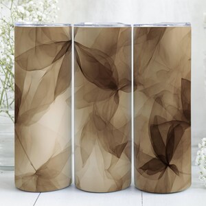 Puede incluir: Tres vasos altos y cilíndricos con un diseño floral abstracto repetido en tonos marrones y beige. El diseño se asemeja a pétalos u hojas superpuestos. Los vasos están sobre un fondo suave y neutro.