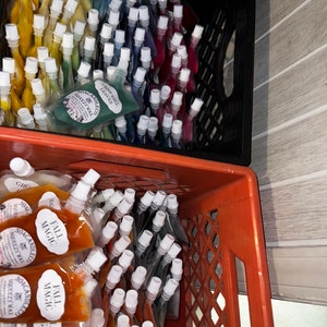 May include: Two crates filled with small, clear plastic pouches containing colorful wax melts. The pouches are labeled "Soacandle.co" and "Squeezy Wax". The top crate has pouches labeled "Crisp Ball Leaves" and the bottom crate has pouches labeled "Fall Magic".