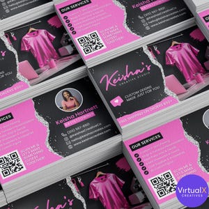 May include: A pile of business cards with a pink and black design. The cards feature the text "Keisha's Creative Studio" and include a QR code. The cards also display a photo of a woman and list services like custom t-shirt printing.
