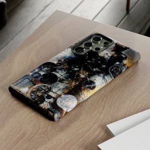 May include: A phone case with a colorful abstract design featuring a variety of shapes and textures. The case has a black camera bump with a gold trim.