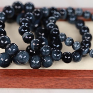 May include: A set of four blue tiger's eye beaded bracelets. The bracelets are made of round beads and are stacked on top of each other.